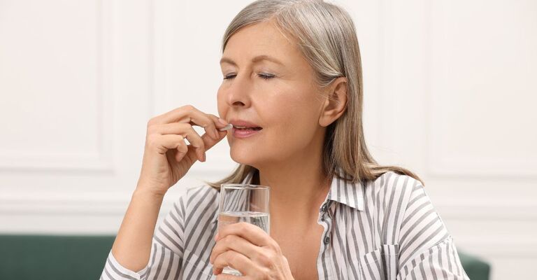 Donna matura assume un integratore con acqua