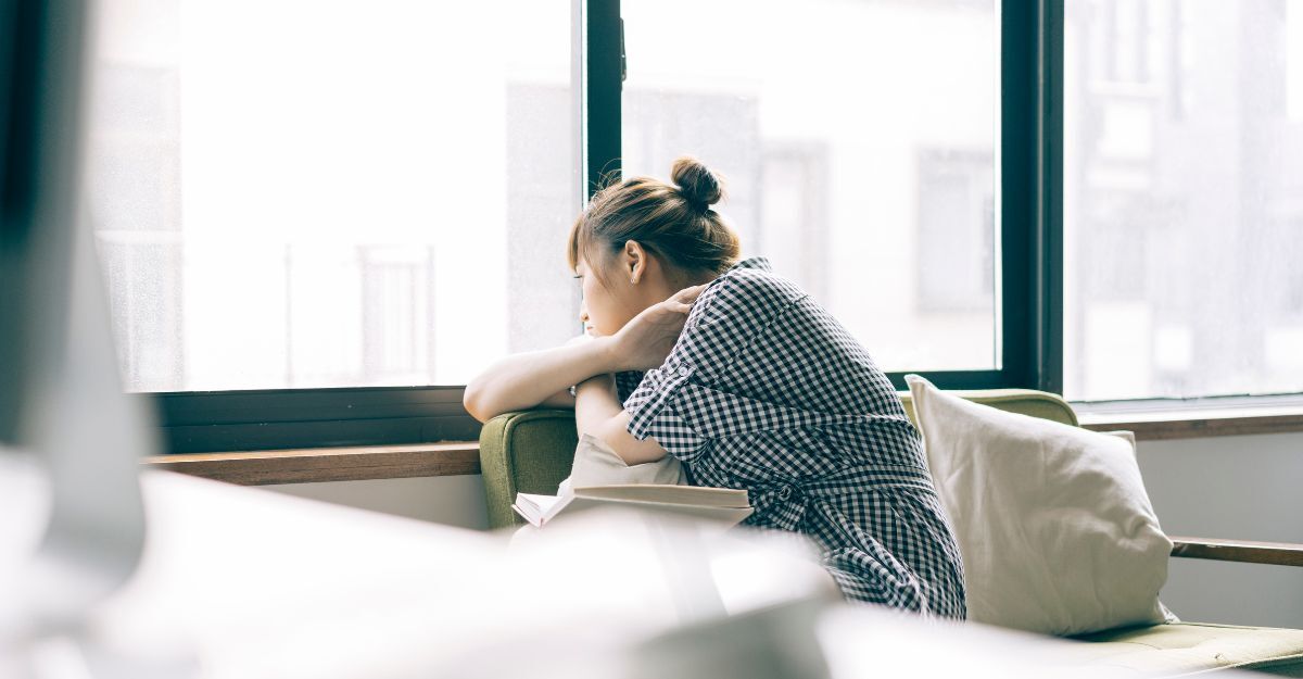 Ragazza che guarda fuori dalla finestra pensierosa