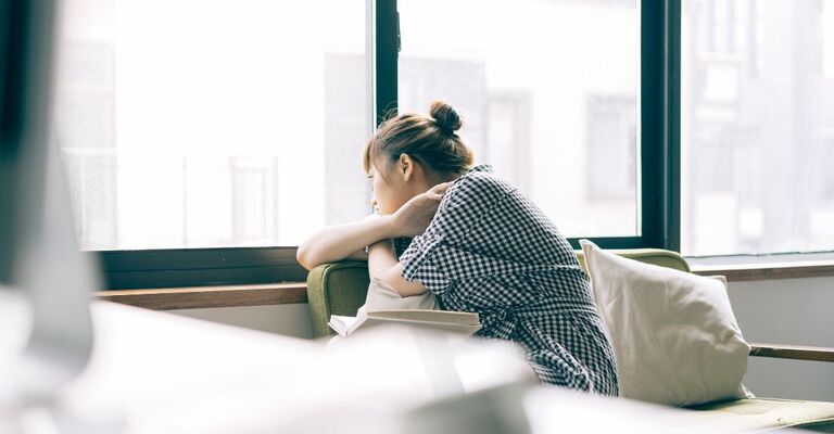 Ragazza che guarda fuori dalla finestra pensierosa