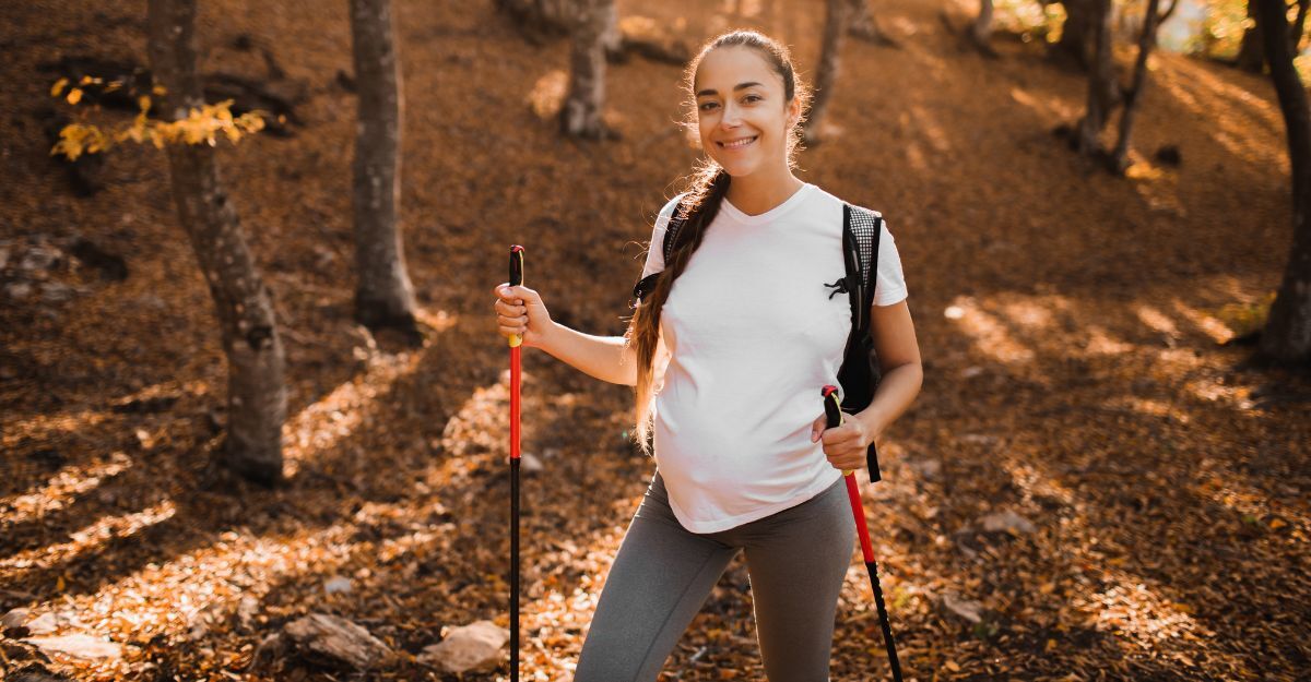 Ragazza giovane incinta che sorride mentre cammina in un sentiero del bosco