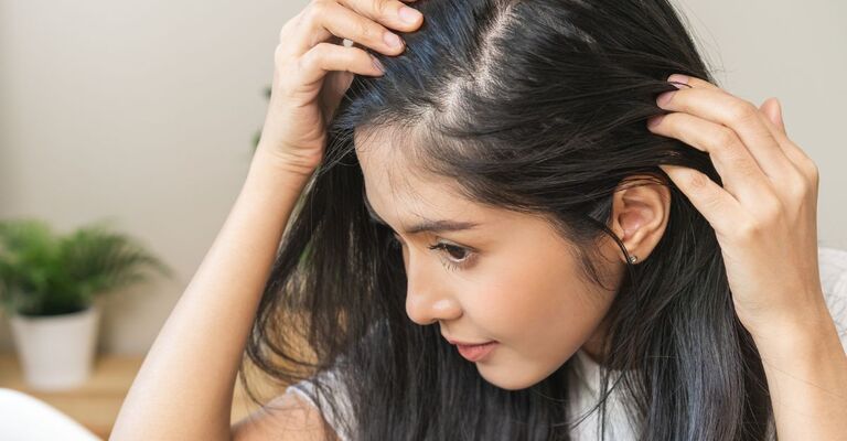 ragazza controlla allo specchio il suo cuoio capelluto