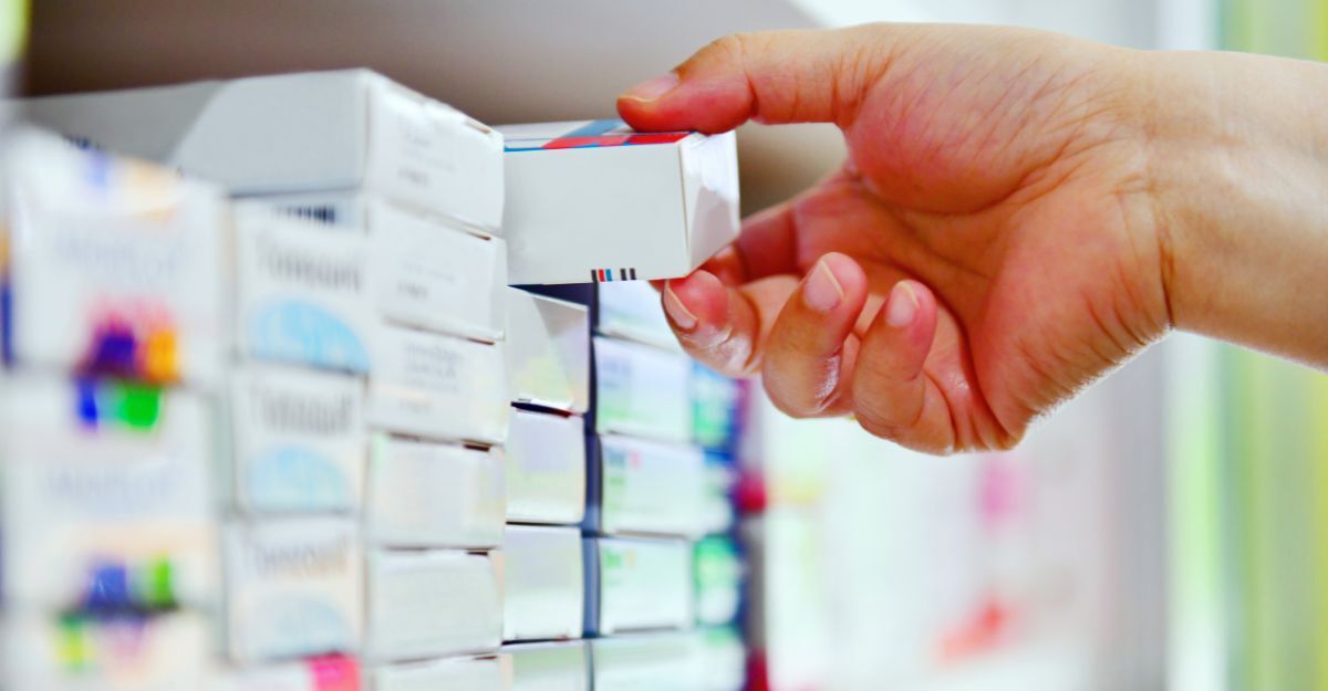 Una mano che prende un farmaco dallo scaffale