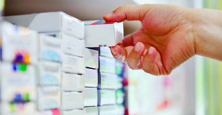 Una mano che prende un farmaco dallo scaffale