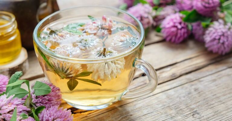 Tisana in tazza con margherite all'interno e fiori intorno