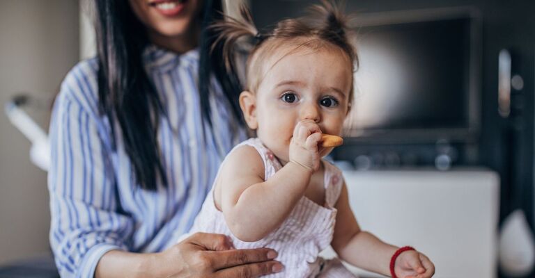 Neonata che mangia un biscotto