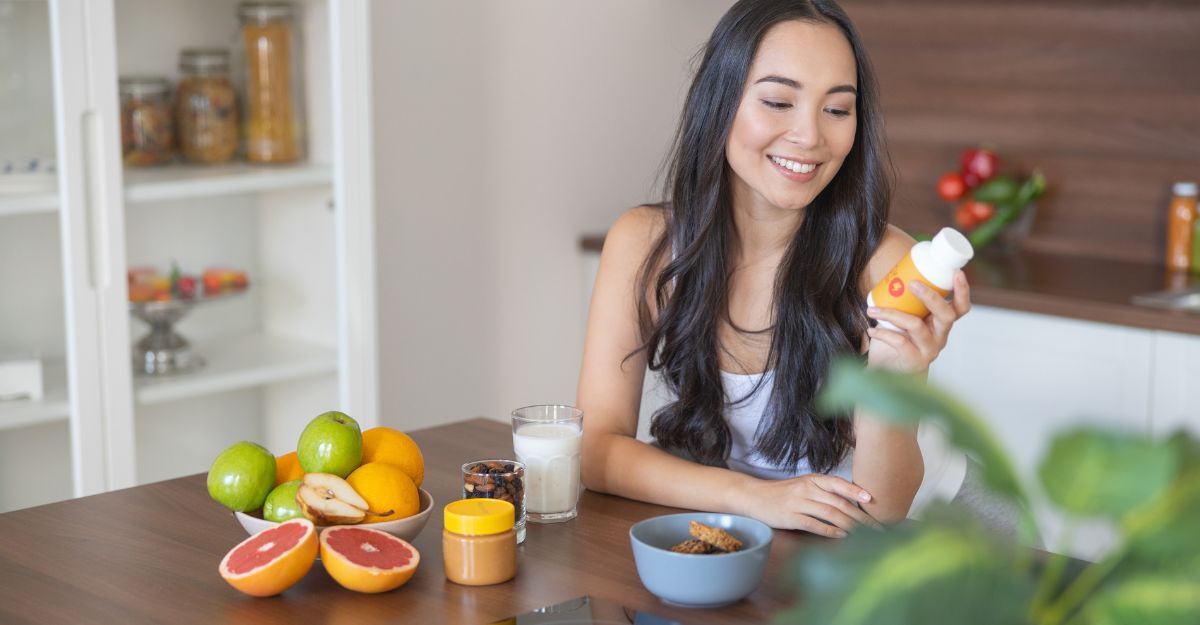 ragazza fa colazione e ha in mano una vasetto di integratori
