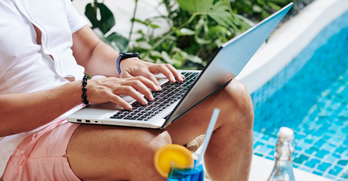 Un ragazzo che lavora al computer vicino ad una piscina