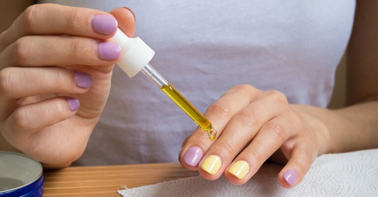 Ragazza mette l'olio sulle unghie delle mani con smalto