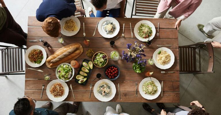 Piatti di pasta sul tavolo mentre le persone si preparano a mangiare