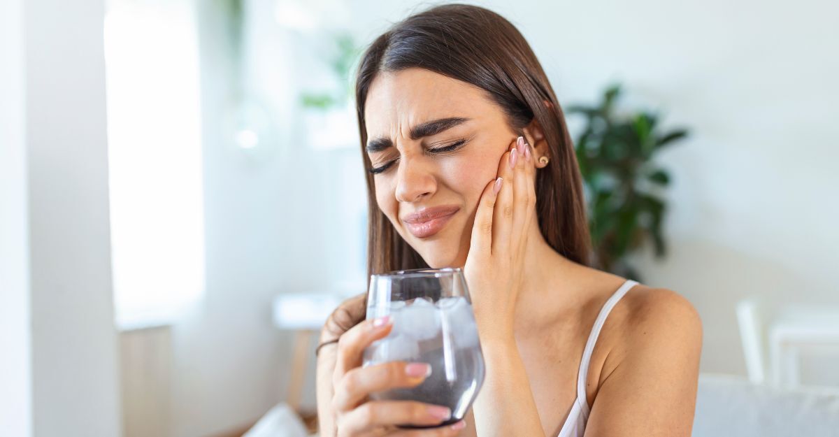ragazza ha un bicchiere di acqua in mano e sente dolore alla bocca