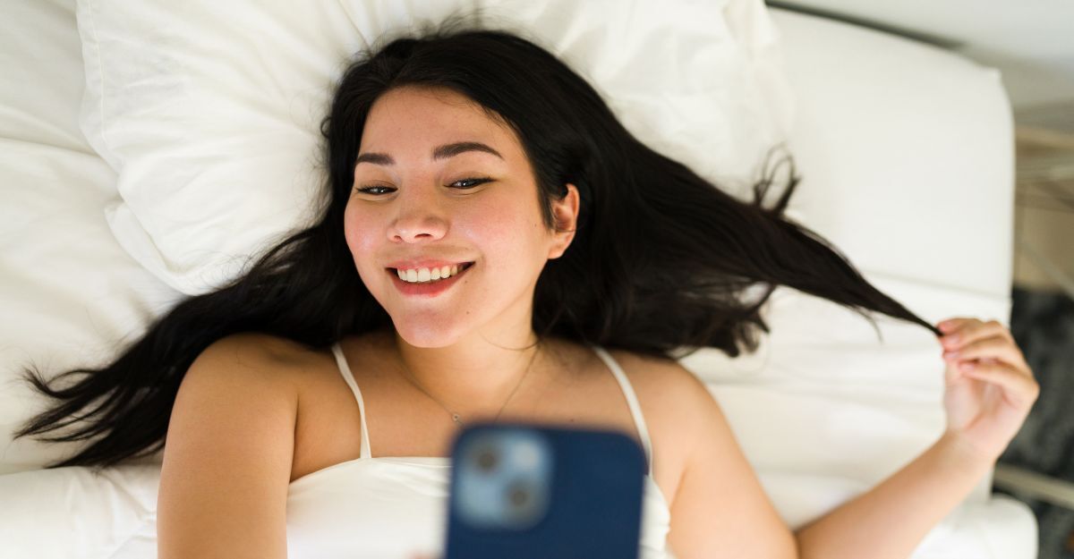 Ragazza si fa un selfie sorridente mentre è sdraiata sul letto