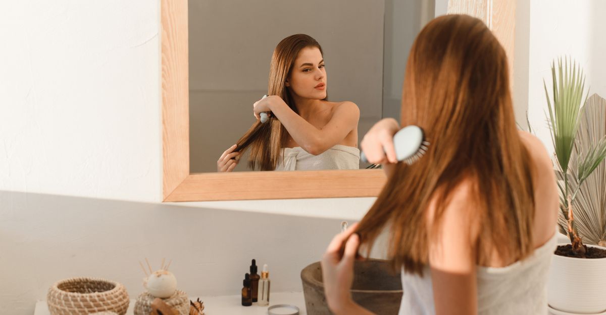 ragazza si pettina i capelli davanti allo specchio