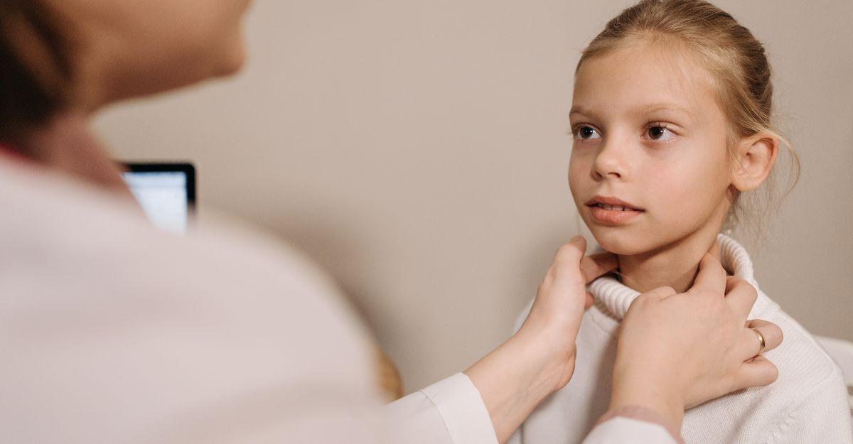 Un medico palpa il collo di una bambina con tonsillite