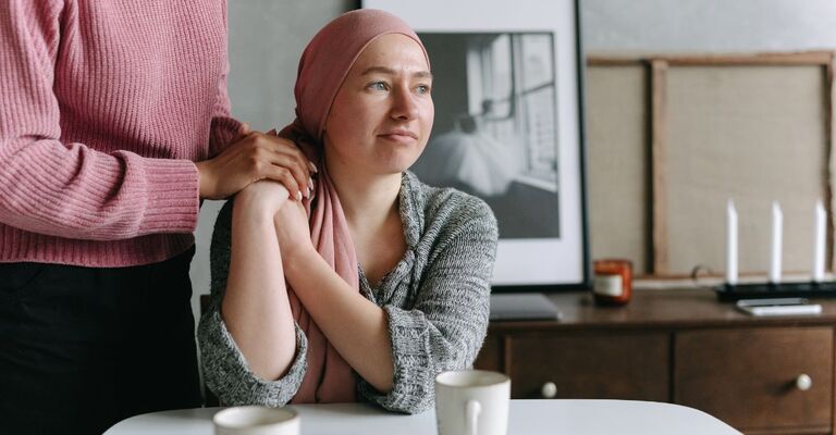 Ragazza con il cancro viene rassicurata con una mano sulla spalla