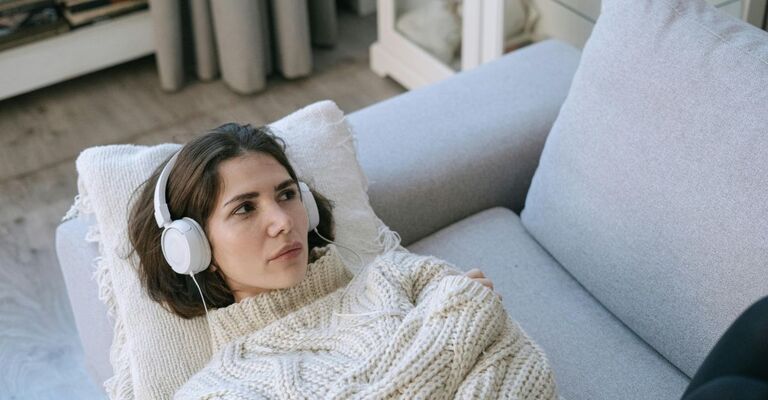 Ragazza sdraiata sul divano con le cuffie