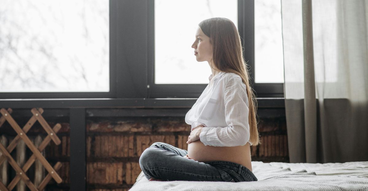 Ragazza incinta sul letto si tocca la pancia