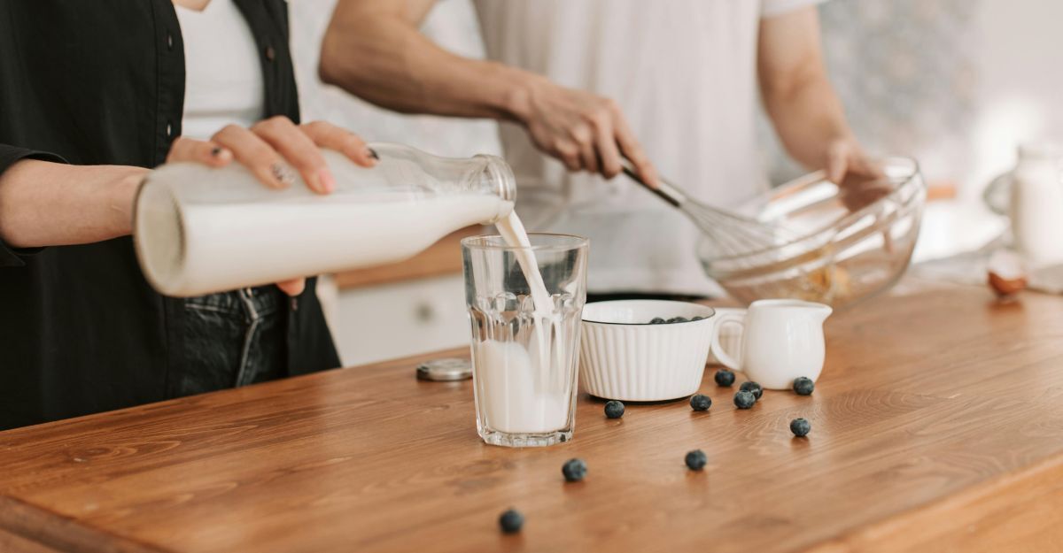 Una persona versa il latte nel bicchiere mentre prepara un dolce con il partner