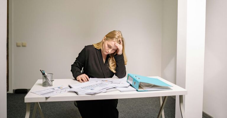 Ragazza seduta alla scrivania che è stressata per il lavoro