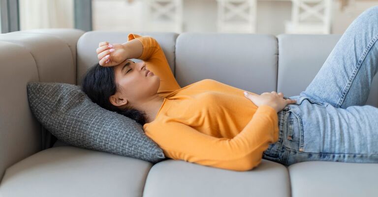 Ragazza sdraiata si tiene la pancia dolorante