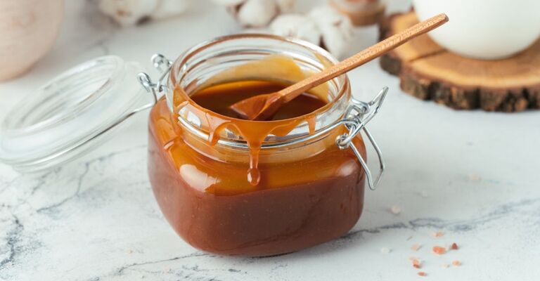 Caramello in un barattolo con un cucchiaino