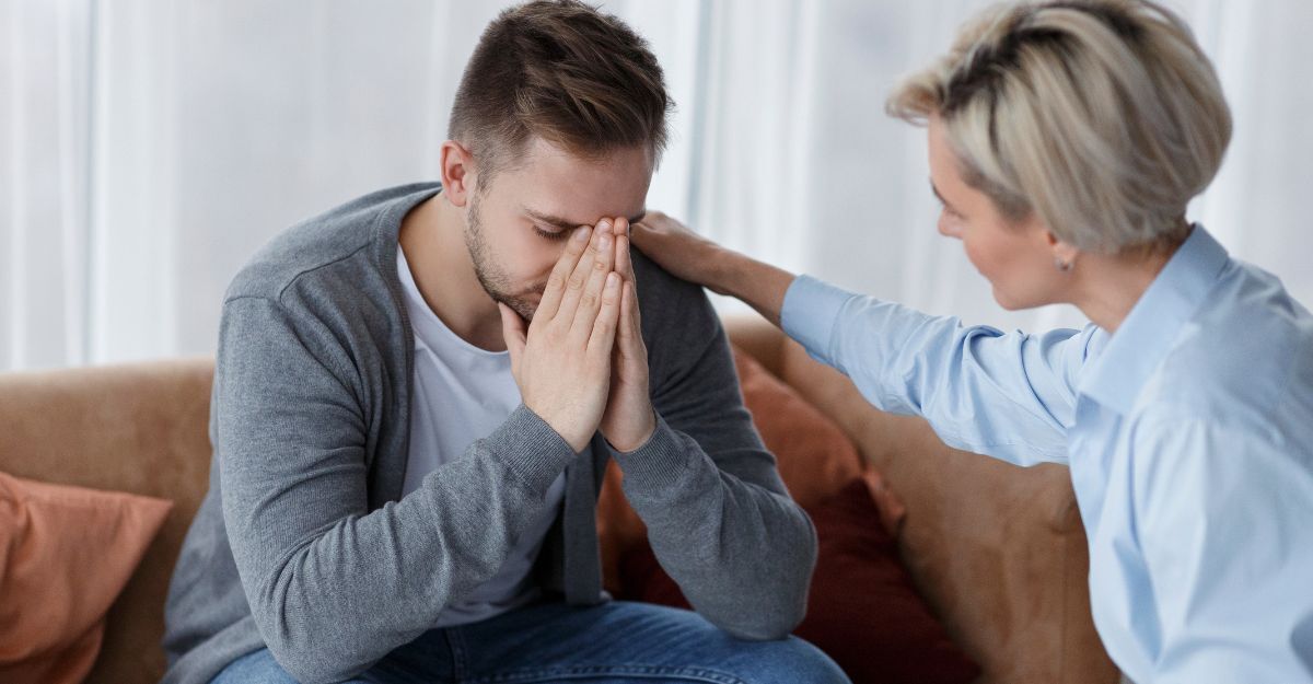 donna consola ragazzo triste seduto sul divano