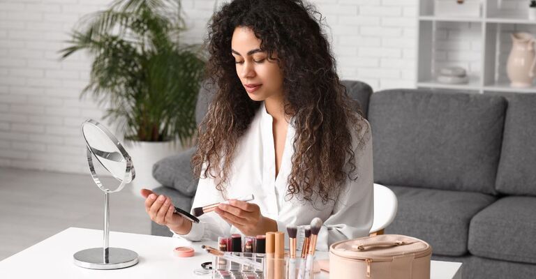 Correttore e fondotinta ragazza si fa il make up davanti allo specchio