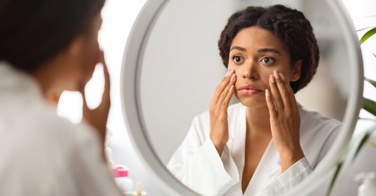 Ragazza si osserva il viso allo specchio