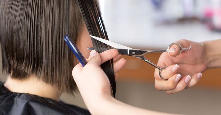 Primo piano di mano con forbici che aggiusta un taglio corto