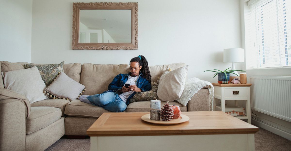 Ragazzo sul divano in casa col telefono in mano
