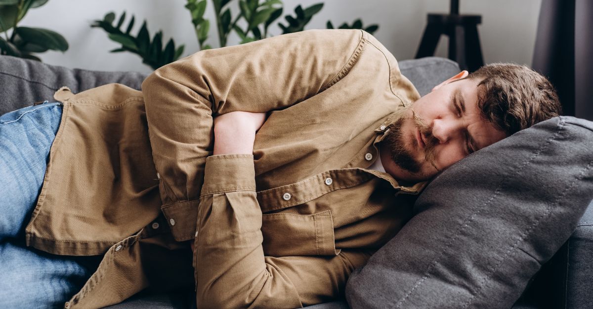 Uomo sdraiato sul divano con mani sulla pancia