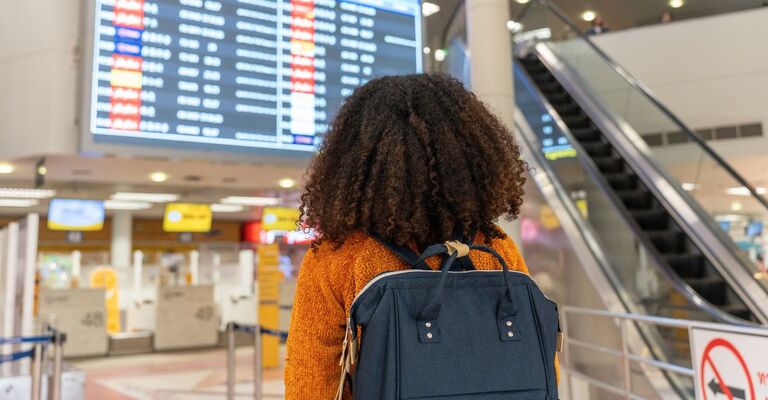 Ragazza guarda il tabellone della partenze in aeroporto