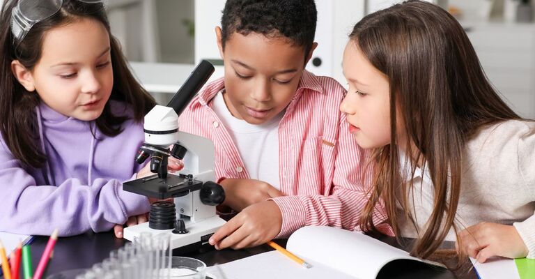 bambini a scuola usano il microscopio