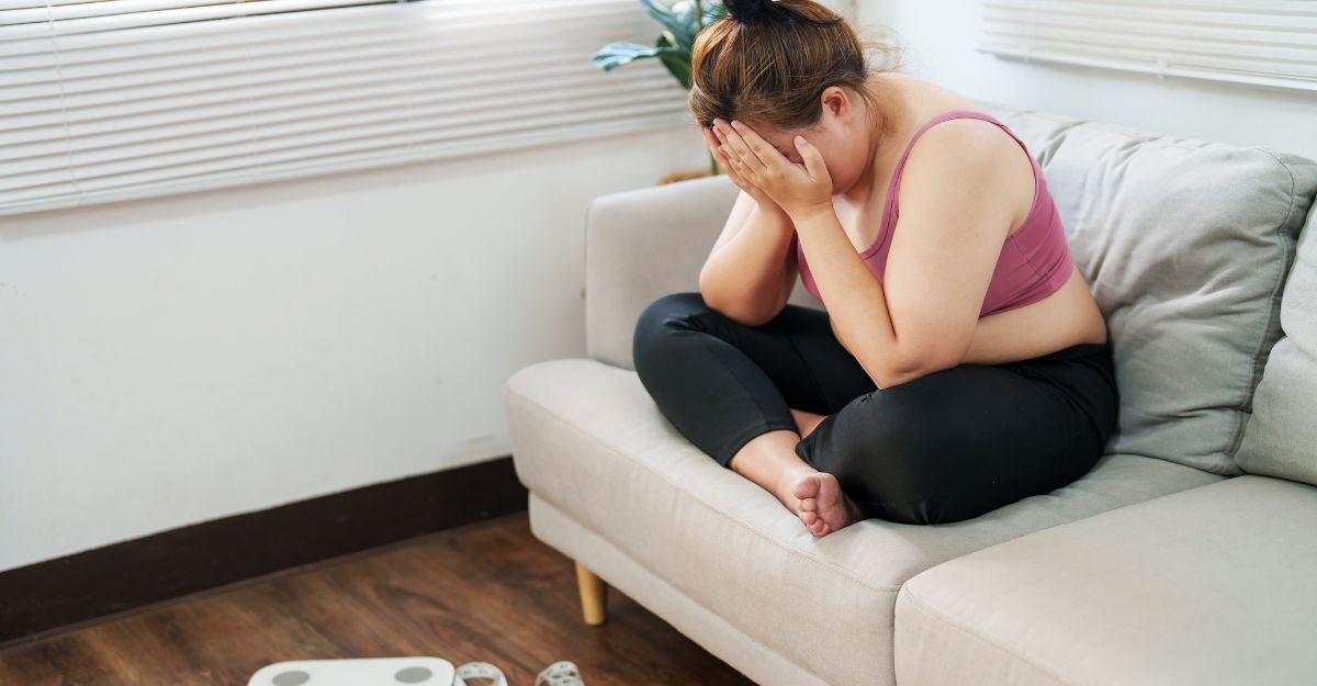 ragazza piange sul divano vicino alla bilancia