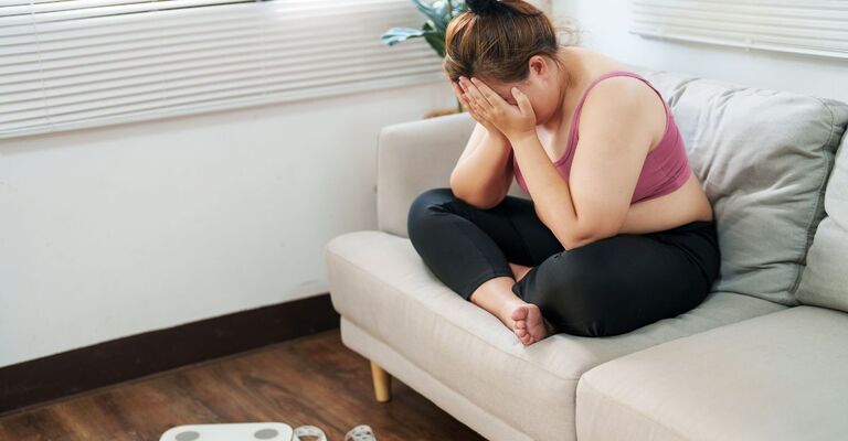 ragazza piange sul divano vicino alla bilancia