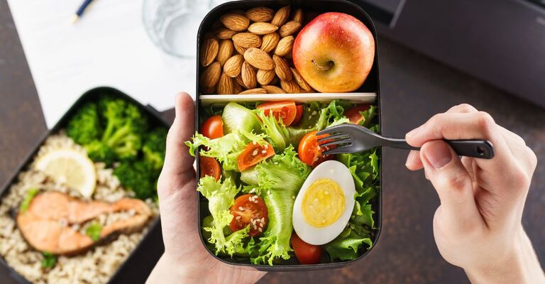 insalata e mela in un contenitore di plastica per pranzo al sacco