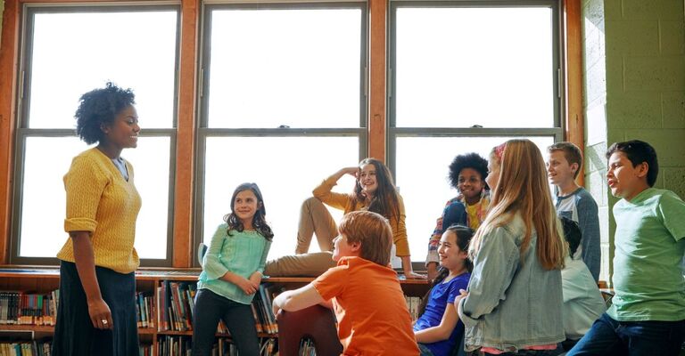 Dei bambini in classe con la maestra fanno mindfulness