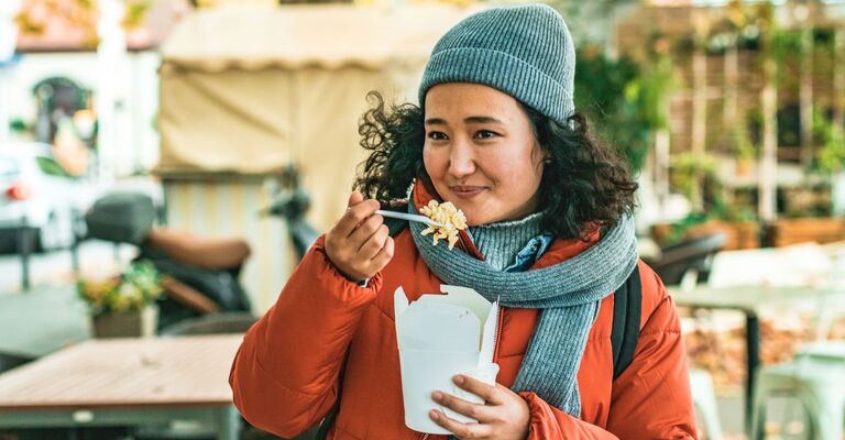 Ragazza magia un piatto da asporto mentre è in giro