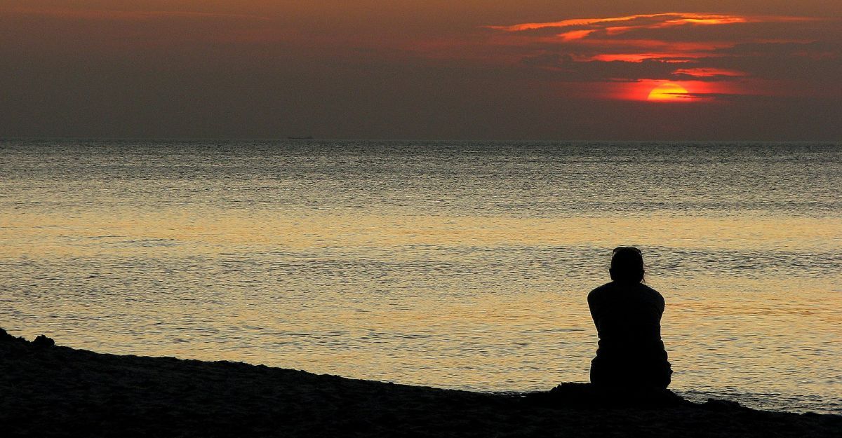 Una persona che guarda il mare al tramonto