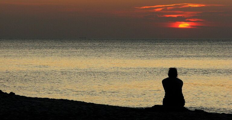 Una persona che guarda il mare al tramonto