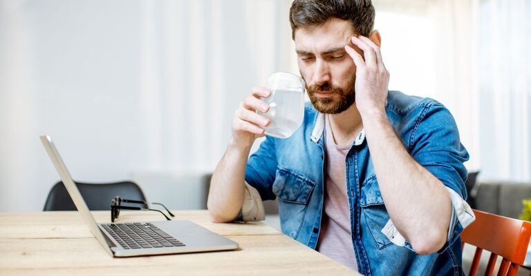 Un uomo beve da un bicchiere