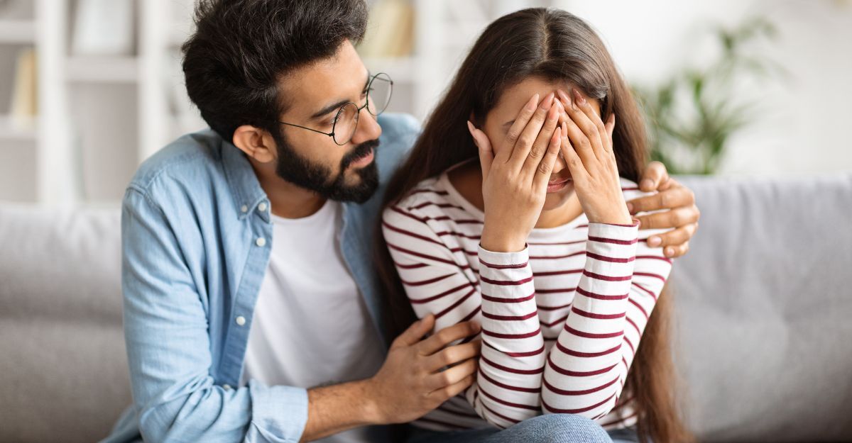 ragazzo abbraccia ragazza che si copre il volto con le mani