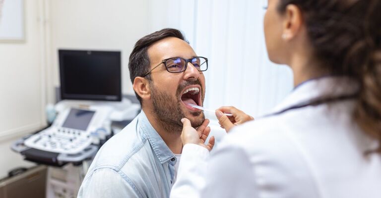 Dottoressa controlla lingua del paziente con una paletta