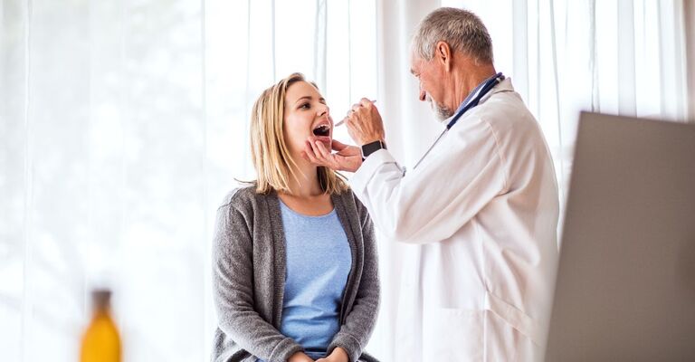 Dottore visita una paziente e osserva la sua lingua