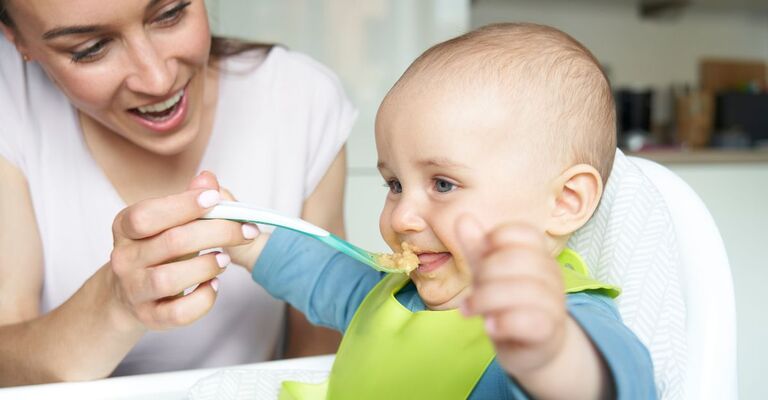 bimbo mangia la pappa dal cucchiaio che gli da la mamma