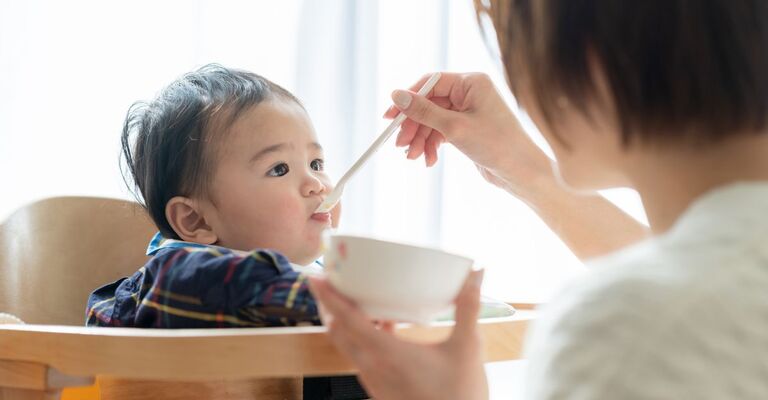 Bambino giapponese nutrito sul seggiolone