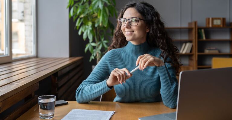 Ragazza seduta alla scrivania che fantastica sul suo futuro