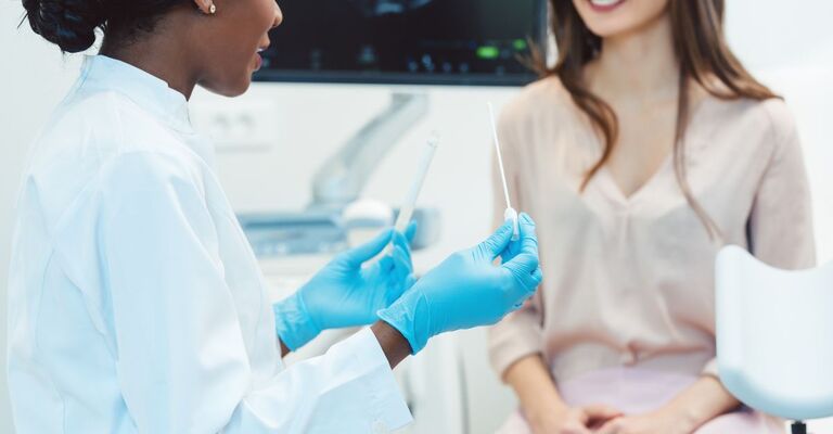 Una ginecologa con in mano un tampone davanti ad una paziente 