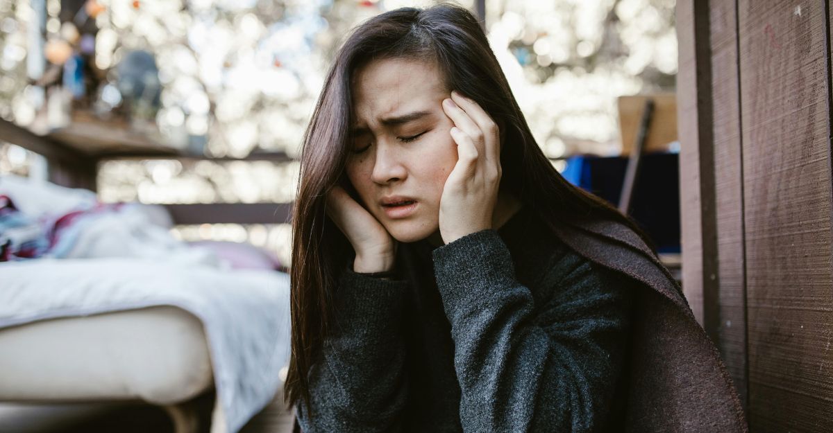 Ragazza che si tiene l'orecchio e la tempia per il dolore