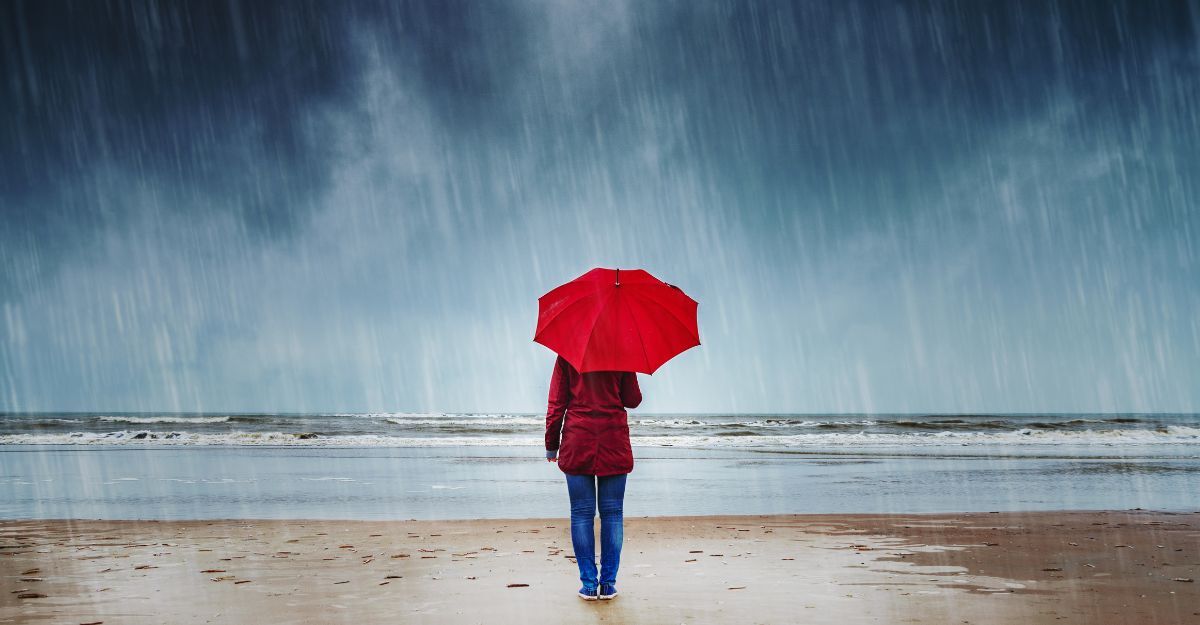 ragazza con ombrello rosse, mentre piove, in riva al mare