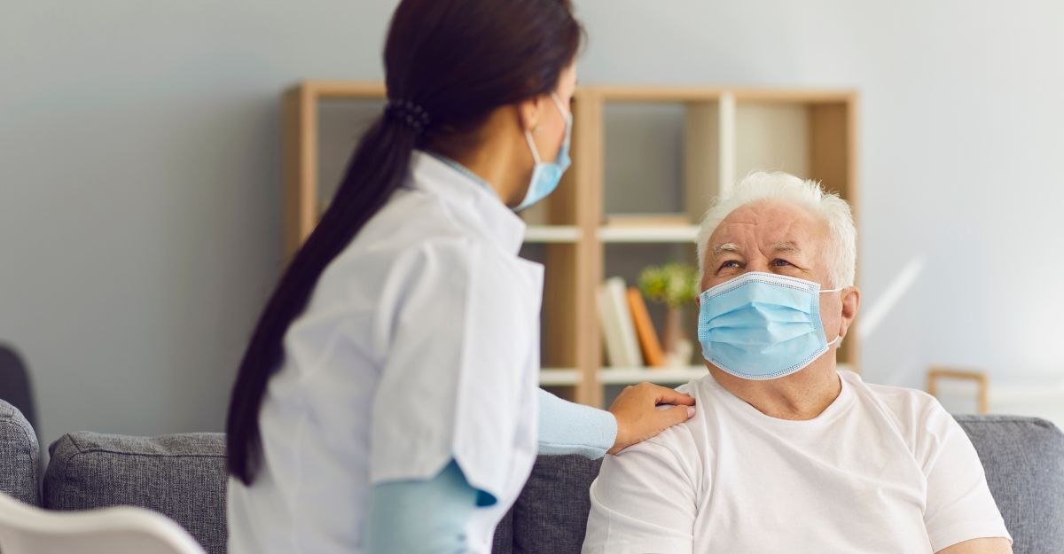 Un medico con la mascherina appoggia una mano sulla spalla di un paziente anziano, anche lui con la mascherina